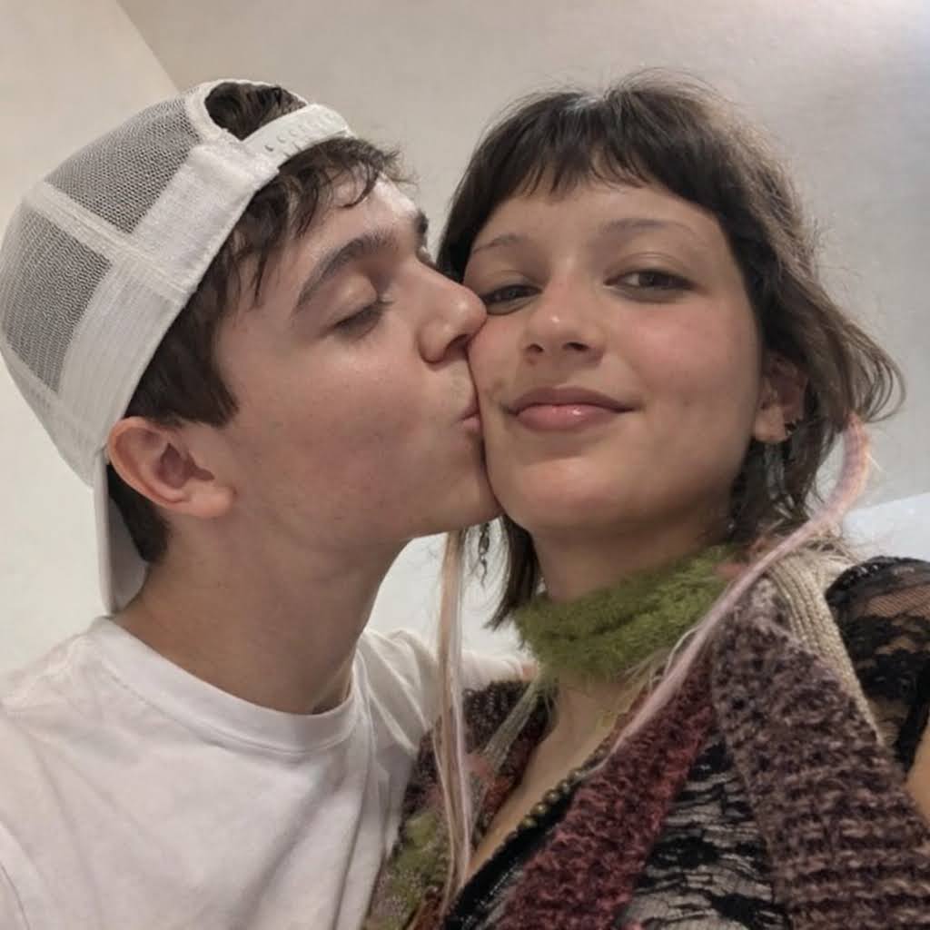 Maicon beijando a bochecha da Vava enquanto ela sorri para a câmera.